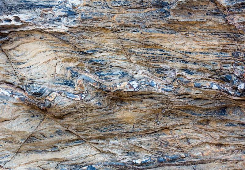 Part of rock close up with impregnation multicolored another geological material in form of snake. Nature background, stock photo