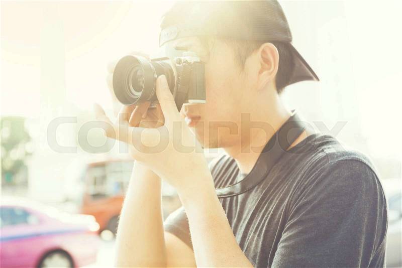 Portrait of young photographer shooting photo with camera in summer evening (Vintage Tone against the sun light), stock photo