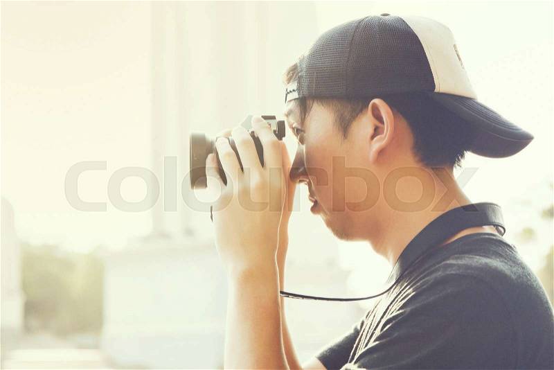 Portrait of young photographer shooting photo with camera in summer evening, stock photo