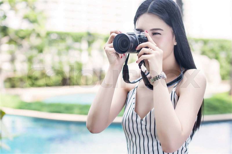 Fashionable and vintage woman taking a photo with vintage camera, stock photo