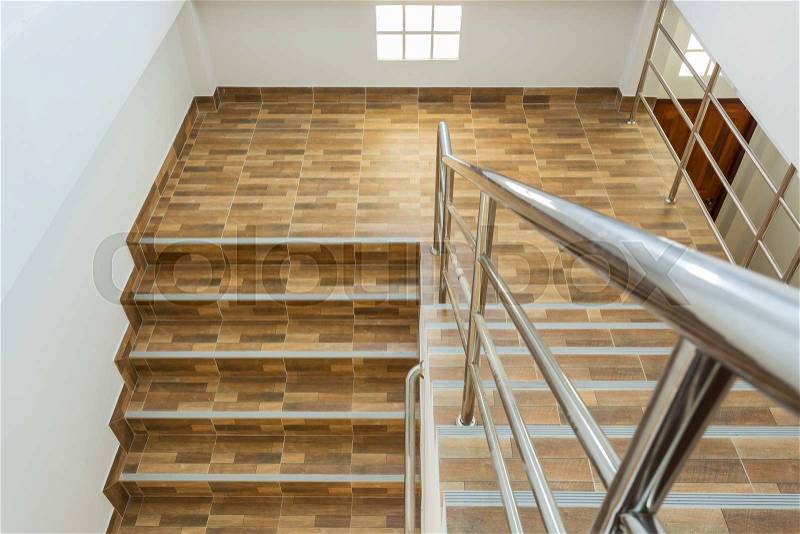 Staircase in residential house with stainless steel banister, ceramic floor tiles wood pattern, stock photo