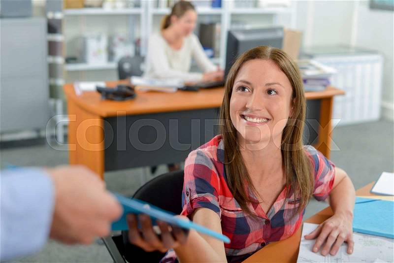 Lady in office being passed a file, stock photo