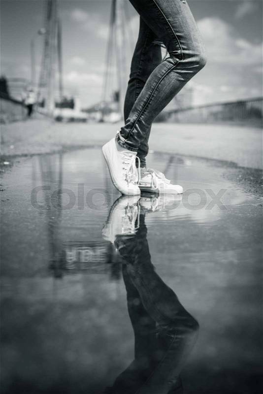 Woman in sport shoes standing in a puddle. Close up shot of foots in a water, stock photo