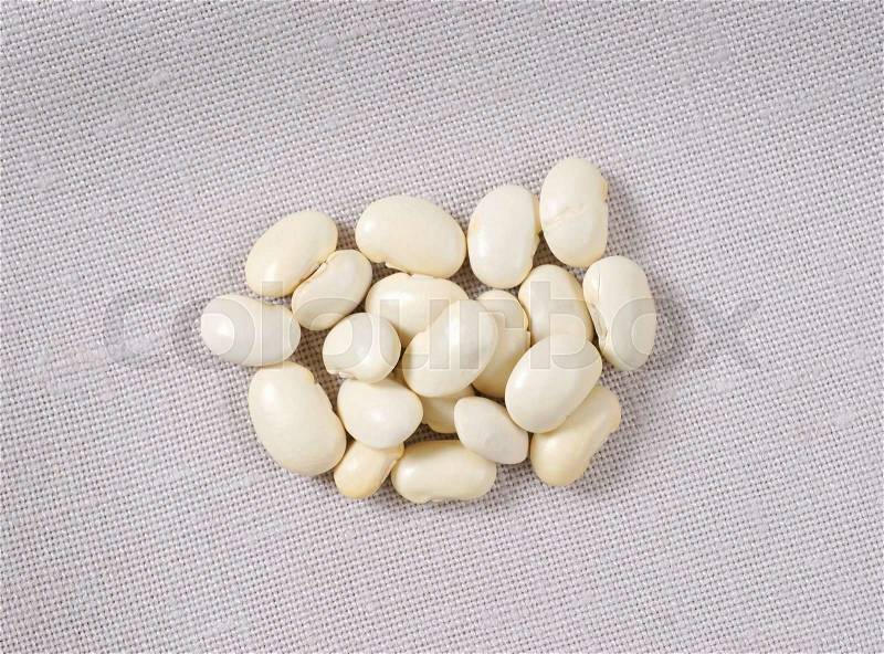 Handful of raw white beans on tablecloth, stock photo