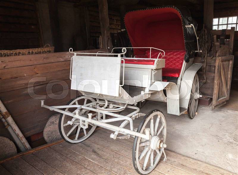 Vintage white coach with red saloon stands in rural garage, stock photo