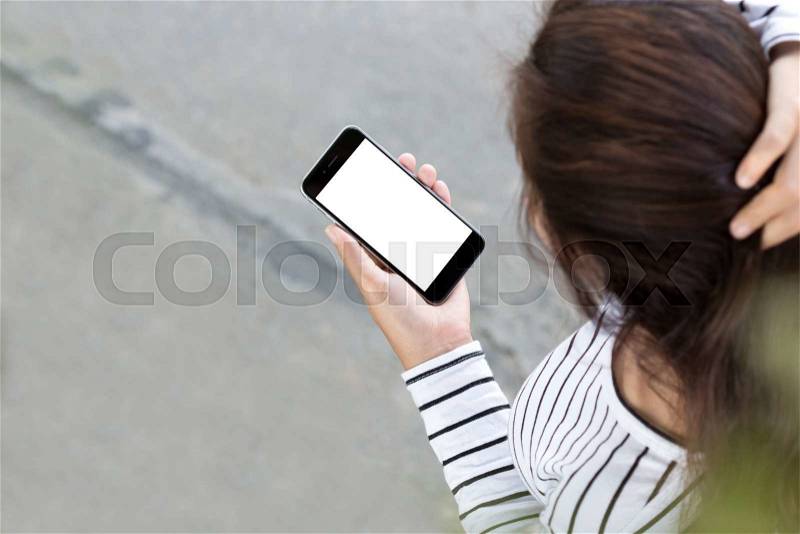 Woman looking on phone and walking on road, third-person view, stock photo