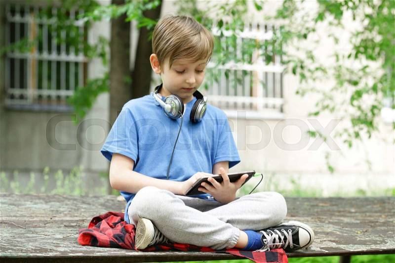 The boy listens to music outside in the park, stock photo