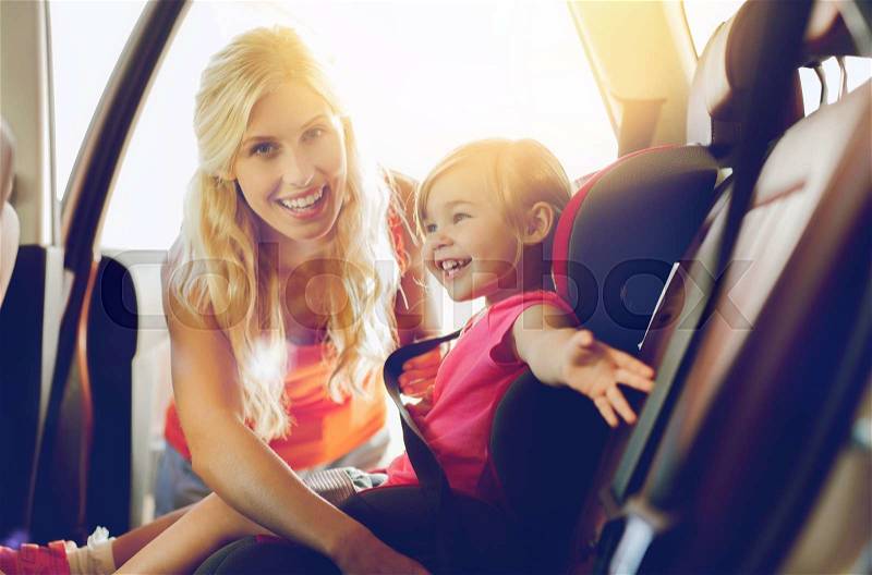 Family, transport, safety, road trip and people concept - happy mother fastening child with car seat belt, stock photo