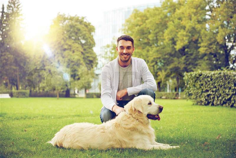 Family, pet, animal and people concept - happy man with labrador retriever dog walking in city park, stock photo