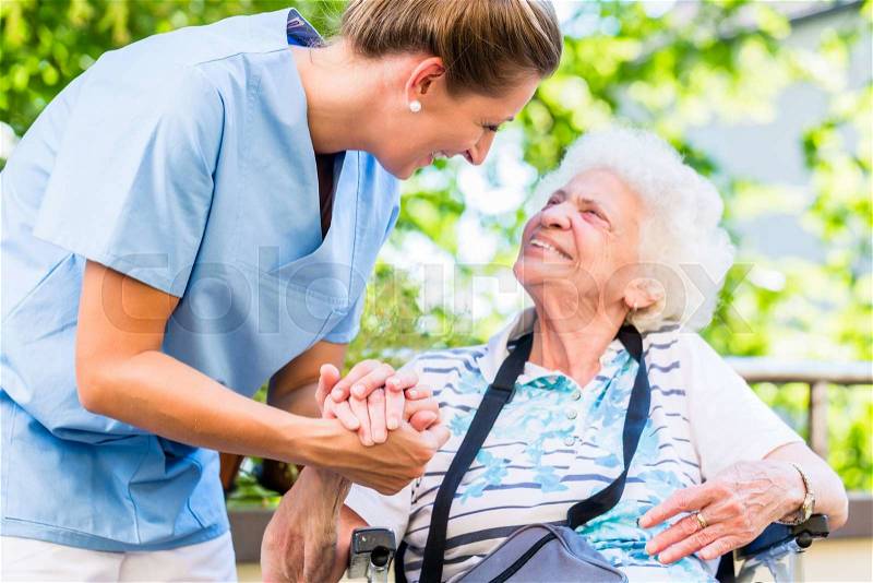 Nurse holding hand of senior woman in pension home, stock photo