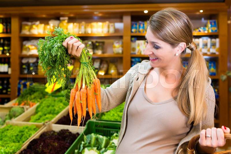 Pregnant woman buying healthy vegetables in grocer store, stock photo