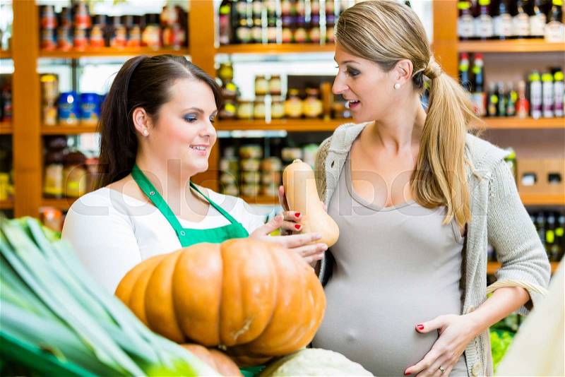 Woman buying pumpkin and vegetables in delicatessen, stock photo