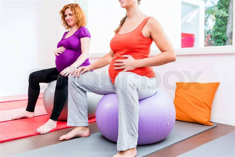 Midwife coaching expectant mothers during relaxation exercises in prenatal class, stock photo