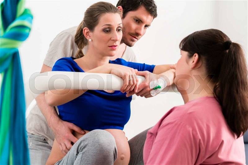 Woman laboring in delivery room with nurse and husband, stock photo