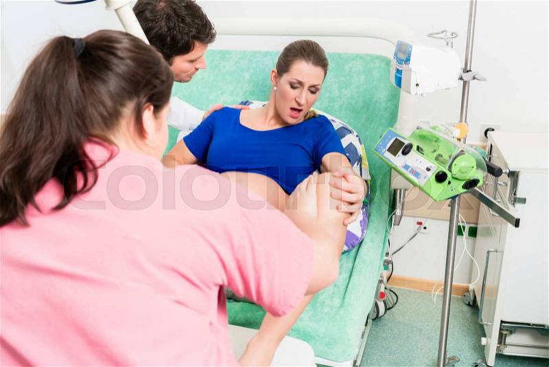 Woman giving birth in labor room of hospital, stock photo