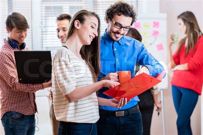 People in young business in casual meeting looking into documents, stock photo