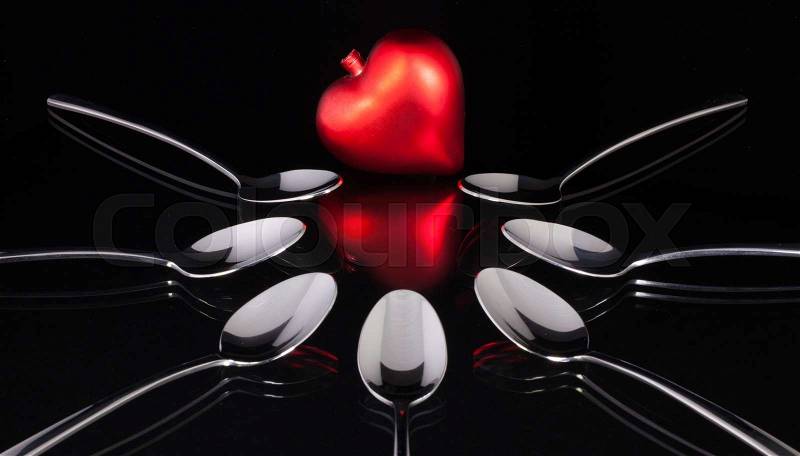 Teaspoons and love symbol on the black glass desk, stock photo