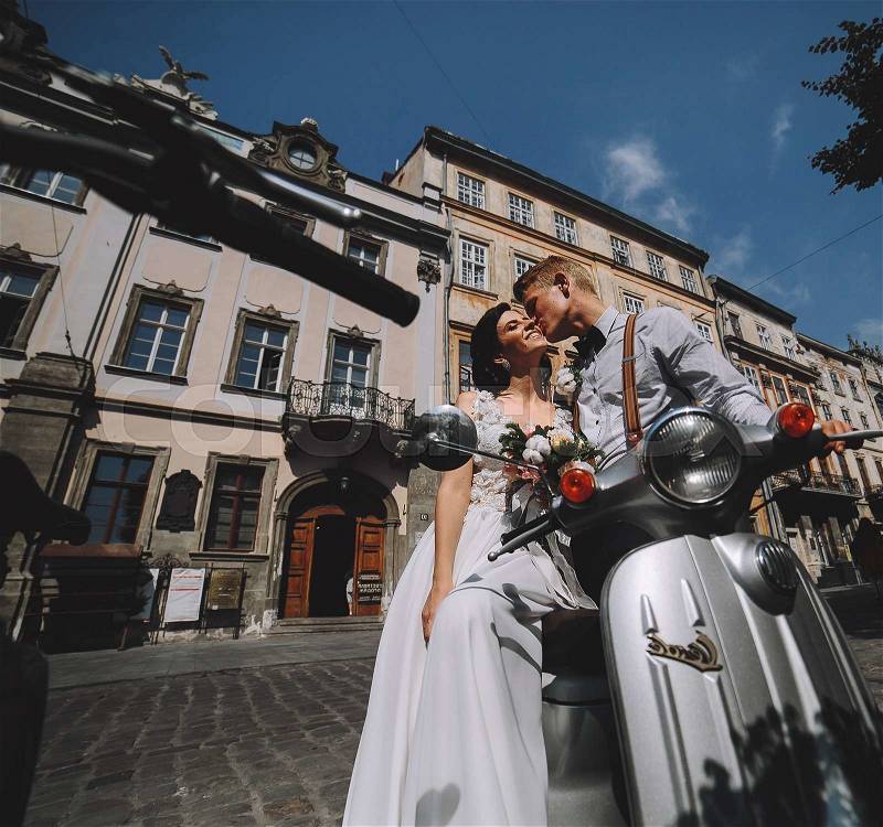 Bride and groom posing on a vintage motor scooter, stock photo
