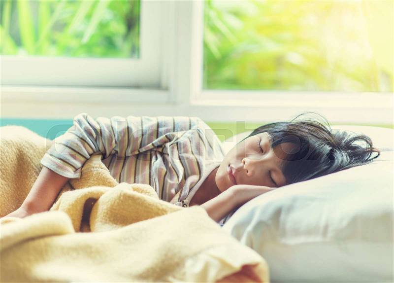Asian girl sleeping on bed covered with blanket, stock photo