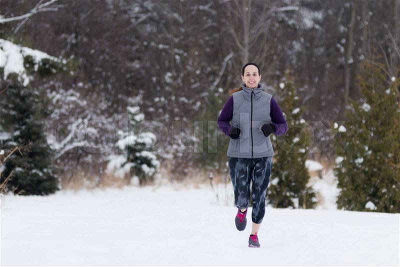 Fitness running woman. Female runner training and jogging outdoors in winter snow. Wellness workout and healthy lifestyle concept with Caucasian female fitness model, stock photo