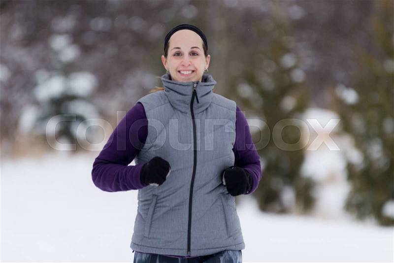 Fitness running woman in winter. Runner closeup of happy active sport model jogging in snow in winter forest, stock photo