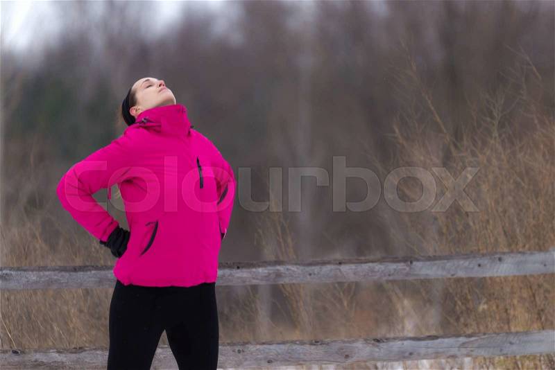 Fit sporty woman stretches with eyes closed. Outdoor winter forest. Fit healthy lifestyle concept with beautiful young fitness model, stock photo