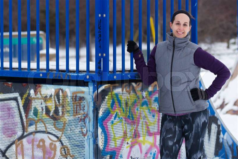 Fit sporty woman outdoors in winter running gear at urban park with graffiti. Fit healthy lifestyle concept, stock photo