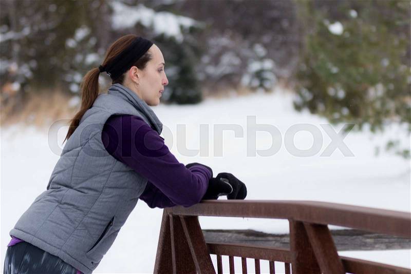 Sporty fit woman in winter running clothing relaxes along nature trail. Fit healthy lifestyle concept with beautiful young fitness model, stock photo