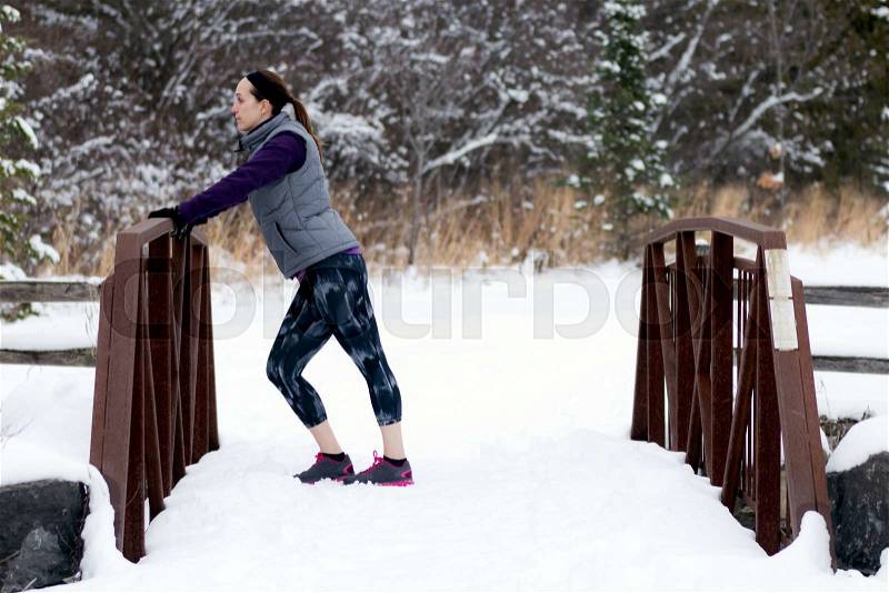 Sporty fit woman in winter running clothing relaxes along nature trail. Fit healthy lifestyle concept with beautiful young fitness model, stock photo