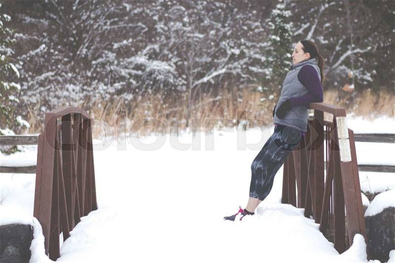 Sporty fit woman in winter running clothing relaxes along nature trail. Fit healthy lifestyle concept with beautiful young fitness model - filter added, stock photo