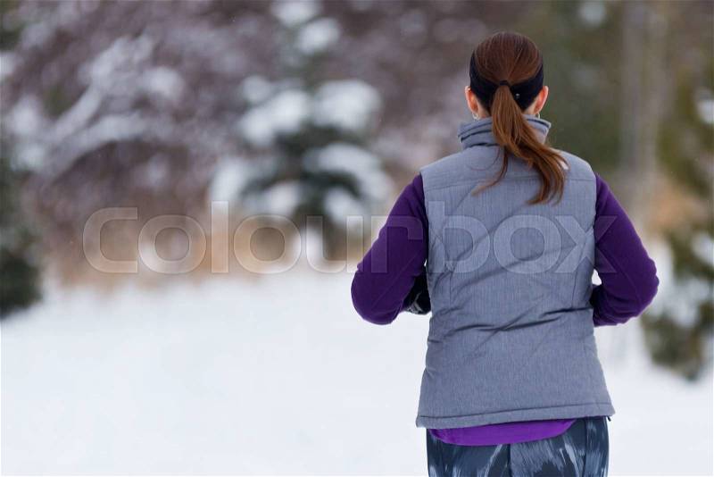 Woman running away from camera outside on cold winter day. Fit healthy lifestyle concept, stock photo