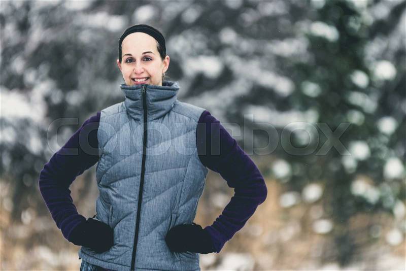 Smiling, happy fit, sporty woman on nature trail during winter. Wellness workout and healthy lifestyle concept - filter added, stock photo