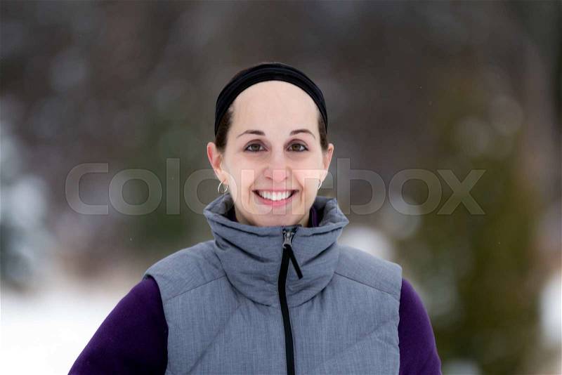 Smiling, happy fit, sporty woman on nature trail during winter. Wellness workout and healthy lifestyle concept, stock photo