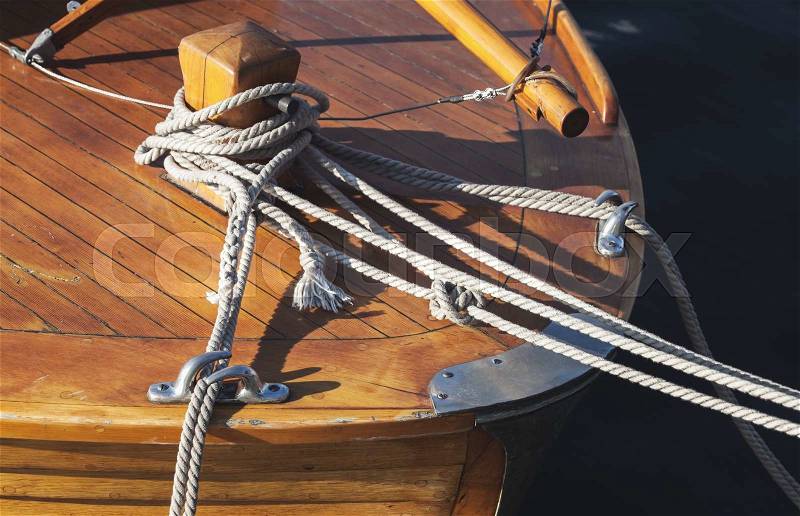 Wooden sailing ship bow fragment with bollard and mooring ropes, stock photo
