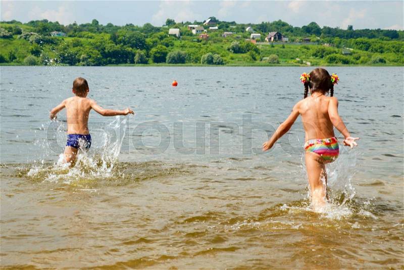 Children running to swim in the river. Summer holidays in the countryside, stock photo