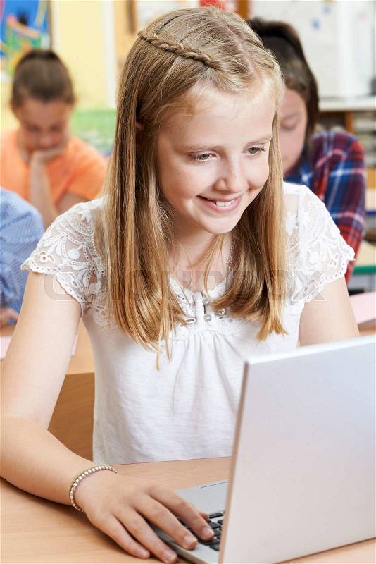Female Elementary School Pupil Using Laptop In Computer Class, stock photo