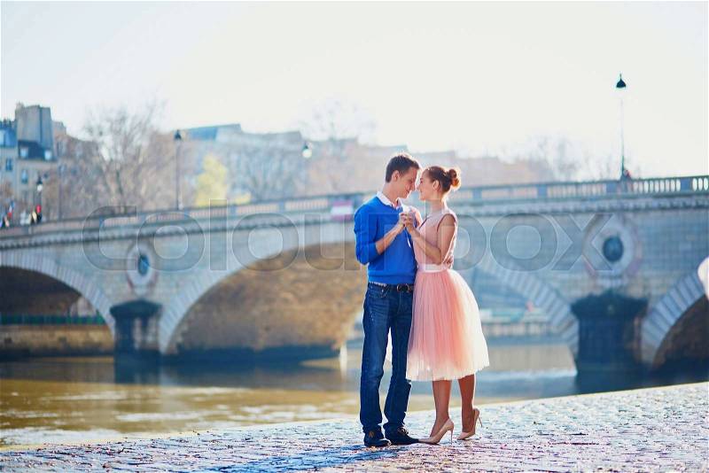 Young romantic couple on the Seine embankment in Paris, France, stock photo