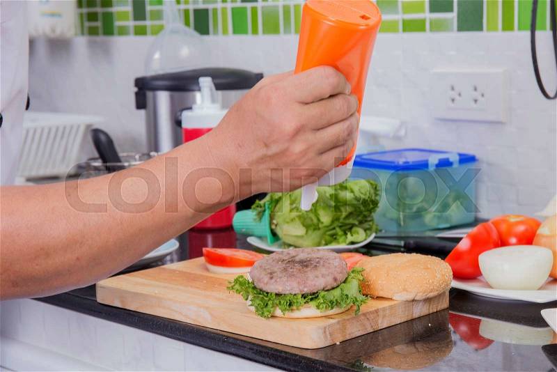 Chef putting mayonnaise on the Hamburger bun /Cooking Hamburger concept, stock photo