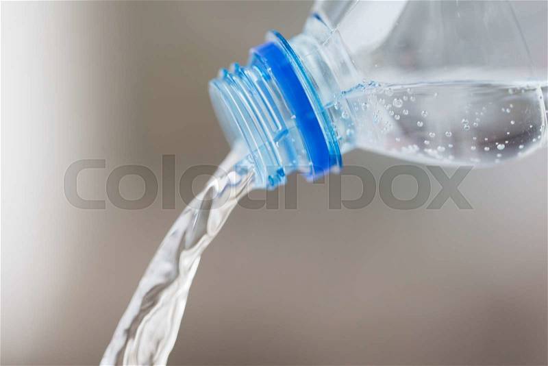 Drinking, healthy eating and food storage concept - close up of water pouring from plastic bottle, stock photo