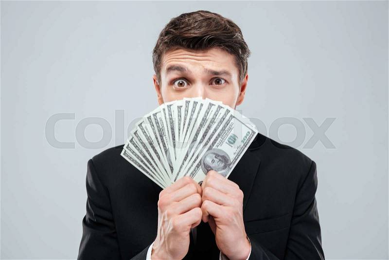 Confused young businessman covered his face with money over white background, stock photo