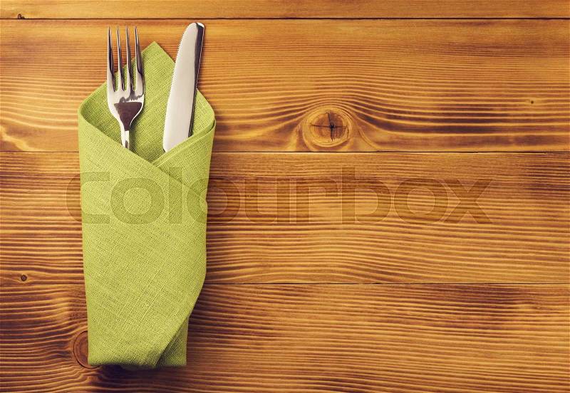 Knife and fork at napkin on wooden background, stock photo