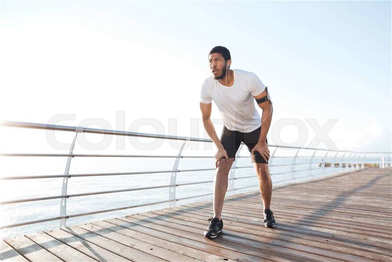 Focused sportsman is ready to start running on pier, stock photo
