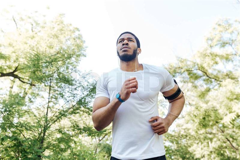 Focused african american young sportsman running outdoors, stock photo