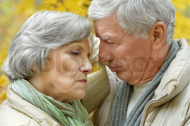 Portrait of a sad senior couple in autumn park, stock photo