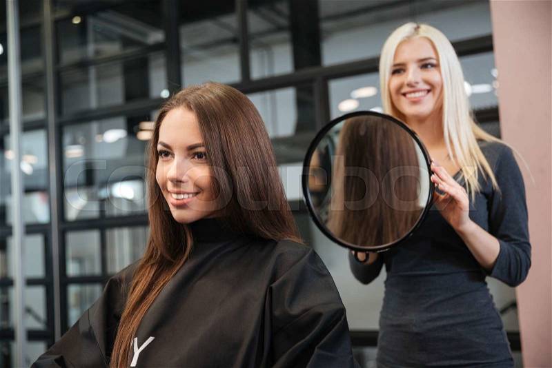 Hairstylist making women\'s haircut to an attractive woman in the beauty salon, stock photo
