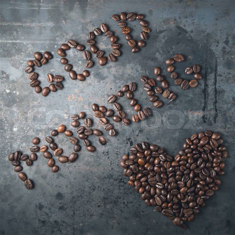Good morning, heart of black coffee beans on dark rustic metal grey background, top view, stock photo