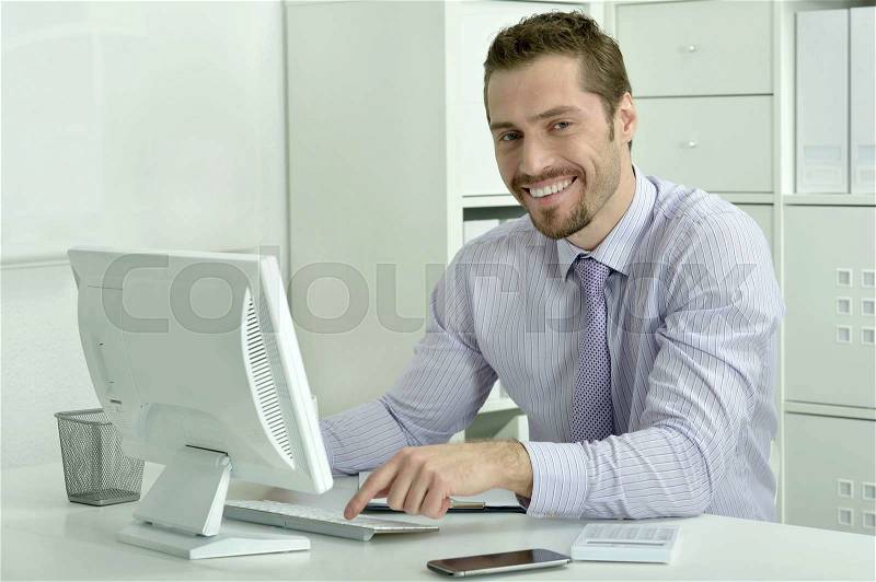 Handsome businessman working with laptop in office, stock photo