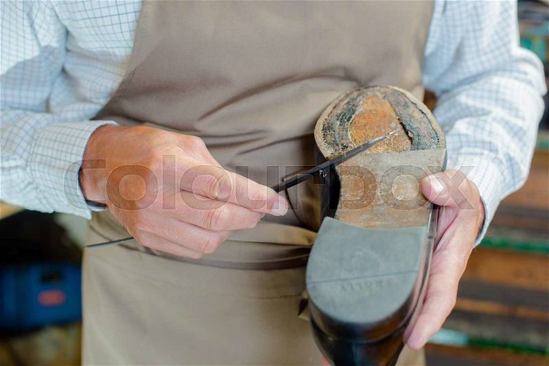 Cobbler mending sole of shoe, stock photo