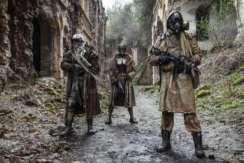 Nuclear post-apocalypse. Survivors in tatters and gas mask on the ruins of the destroyed city, stock photo