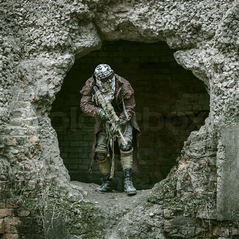 Nuclear post-apocalypse. Sole survivor in tatters and gas mask on the ruins of the destroyed city, stock photo